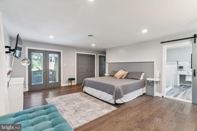 bedroom with a closet, dark hardwood / wood-style flooring, a barn door, ensuite bathroom, and access to exterior