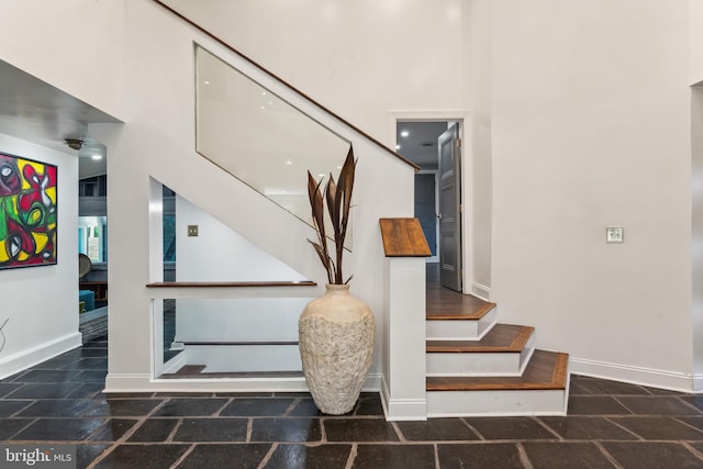 staircase featuring dark tile patterned flooring and a high ceiling