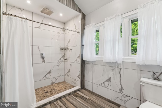 bathroom with a shower with curtain, toilet, and tile walls