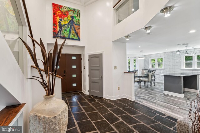 kitchen featuring appliances with stainless steel finishes, dark stone countertops, a kitchen island, and wall chimney exhaust hood