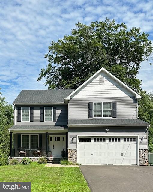 view of front of house featuring a garage, cooling unit, covered porch, and a front lawn