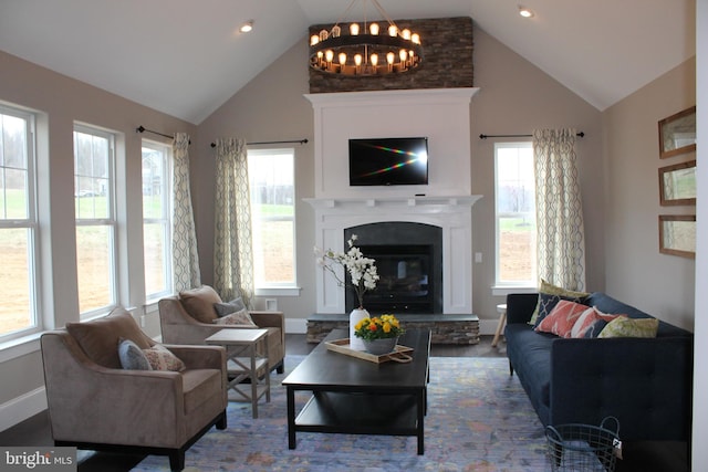 living room featuring wood-type flooring, a stone fireplace, a chandelier, and high vaulted ceiling