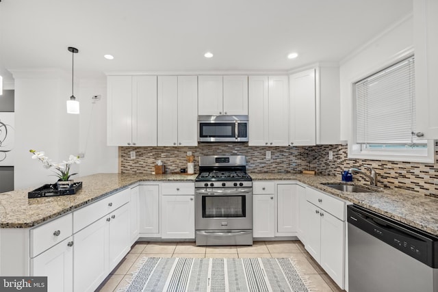 kitchen with sink, stainless steel appliances, kitchen peninsula, pendant lighting, and white cabinets