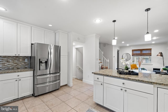 kitchen with decorative backsplash, stainless steel refrigerator with ice dispenser, light stone counters, white cabinetry, and hanging light fixtures