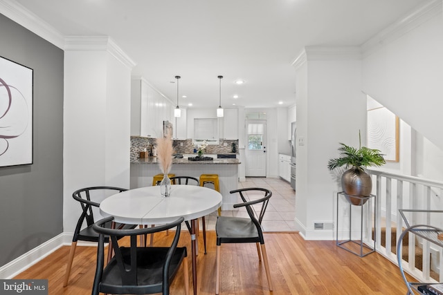 dining room featuring light wood-type flooring and ornamental molding