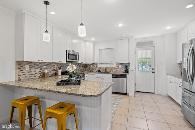 kitchen with pendant lighting, a breakfast bar, kitchen peninsula, and appliances with stainless steel finishes