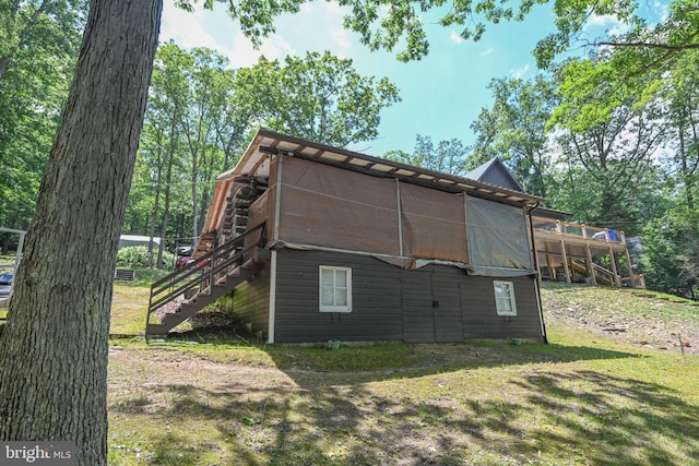 rear view of house featuring a wooden deck and a lawn