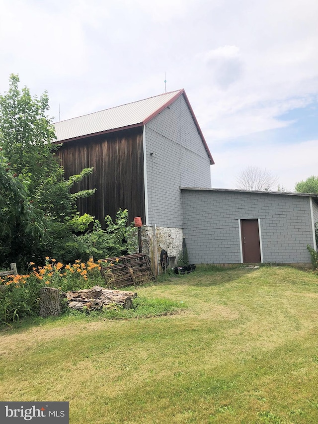 view of home's exterior with a lawn and an outbuilding