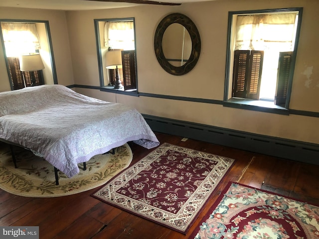 bedroom with dark hardwood / wood-style flooring and a baseboard radiator