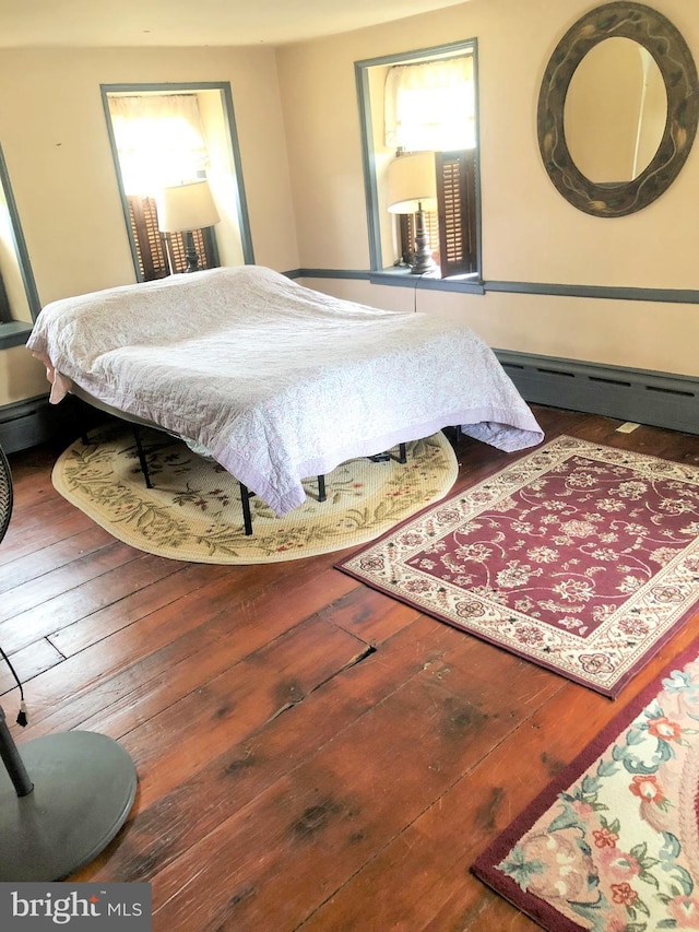 bedroom with dark hardwood / wood-style flooring and a baseboard heating unit