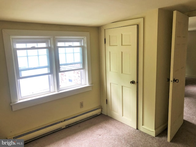 unfurnished bedroom with light colored carpet and a baseboard heating unit