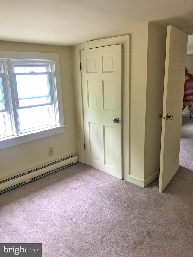 unfurnished bedroom with light carpet and a baseboard radiator