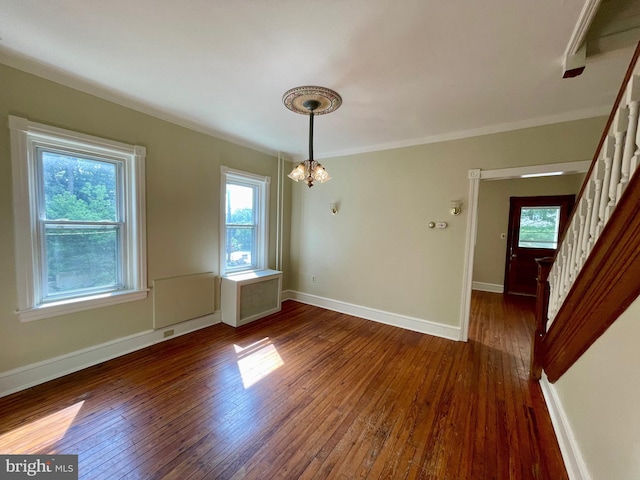 unfurnished dining area featuring dark hardwood / wood-style flooring, crown molding, and a notable chandelier