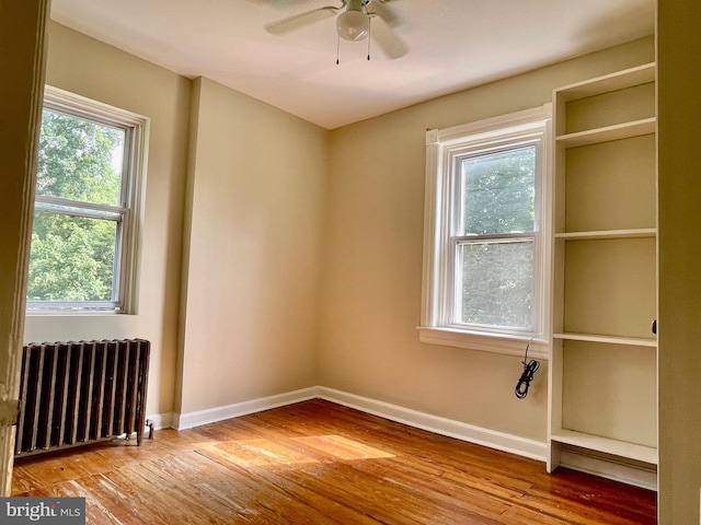 spare room with light hardwood / wood-style flooring, radiator, and ceiling fan