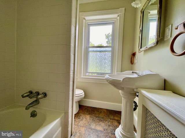 bathroom with tiled shower / bath combo and toilet