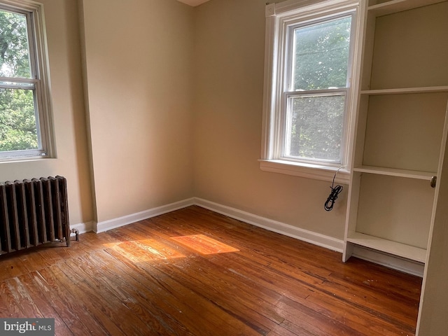 spare room featuring radiator heating unit and wood-type flooring