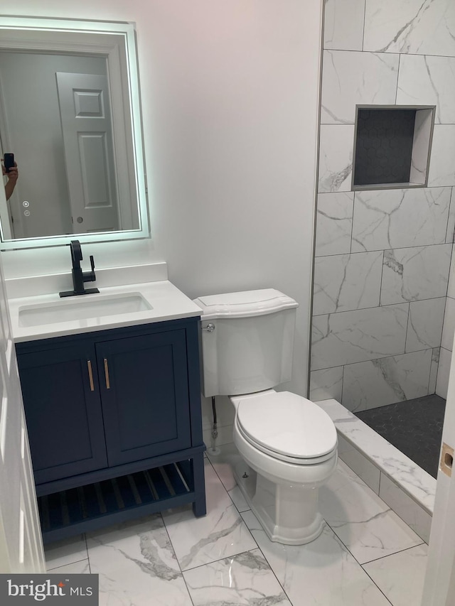 bathroom with vanity, toilet, and a tile shower