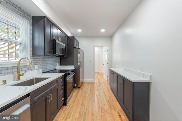 kitchen featuring light stone countertops, stainless steel appliances, sink, and light wood-type flooring