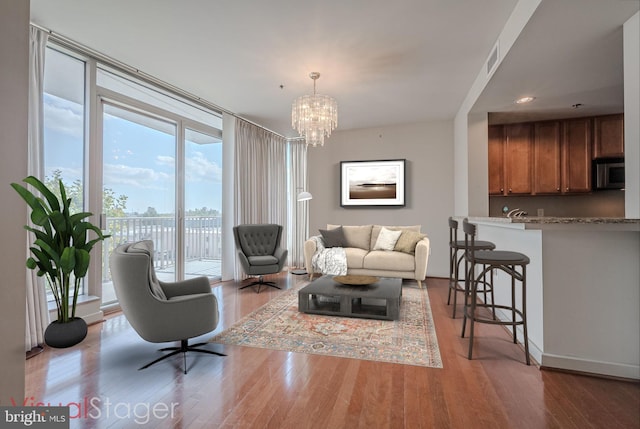 living area with wood finished floors, visible vents, recessed lighting, floor to ceiling windows, and a notable chandelier