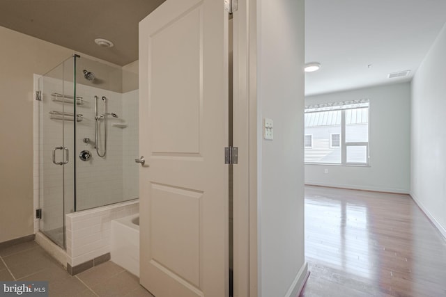 bathroom with hardwood / wood-style floors and shower with separate bathtub