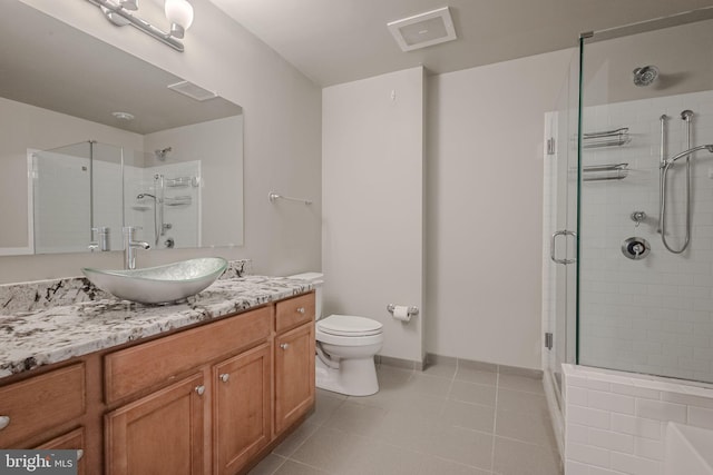 bathroom featuring tile patterned flooring, vanity, toilet, and a shower with door