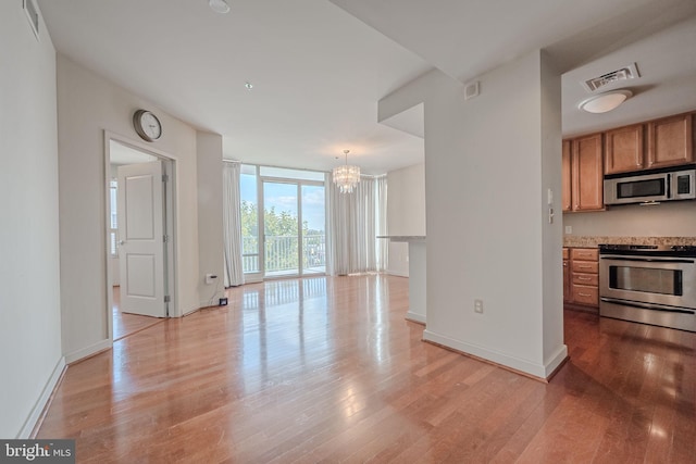 kitchen featuring a notable chandelier, light hardwood / wood-style floors, stainless steel appliances, and hanging light fixtures