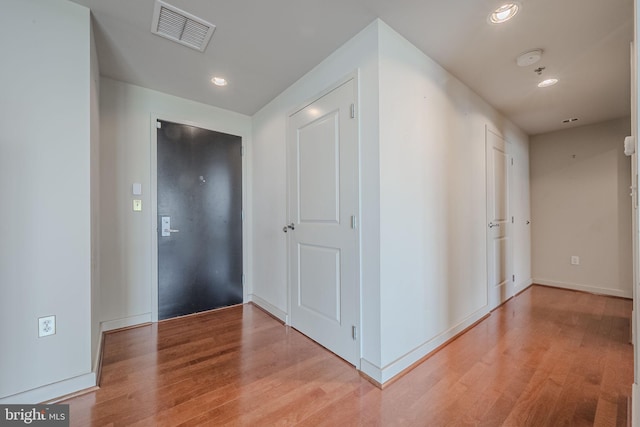 hallway featuring baseboards, light wood-type flooring, visible vents, and recessed lighting