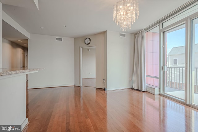 unfurnished living room with an inviting chandelier and light hardwood / wood-style flooring