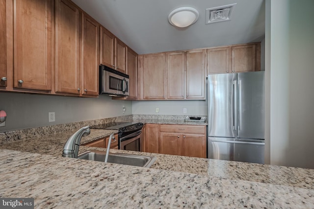 kitchen with stainless steel appliances, light stone counters, lofted ceiling, and sink