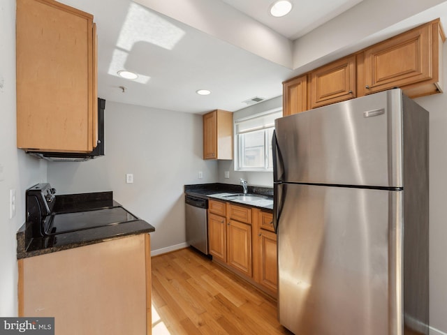 kitchen with light hardwood / wood-style floors, dark stone countertops, sink, and appliances with stainless steel finishes