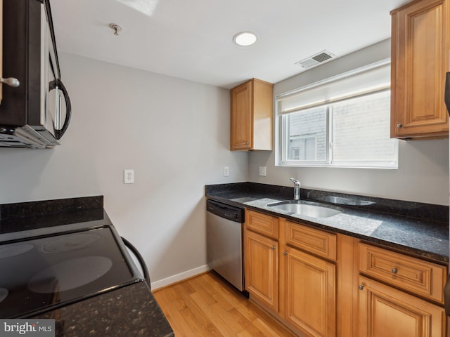 kitchen with dishwasher, stove, sink, dark stone countertops, and light wood-type flooring