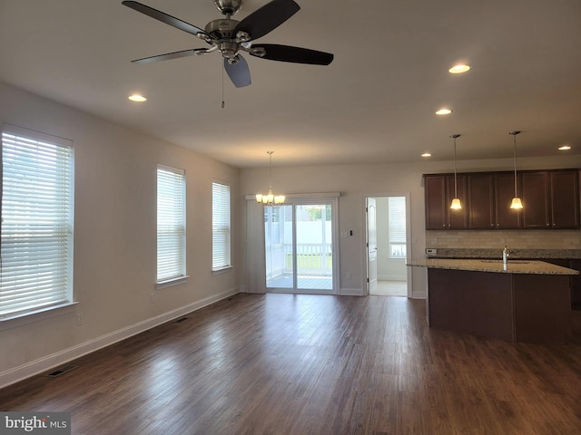 unfurnished living room featuring sink, ceiling fan with notable chandelier, and dark wood-type flooring