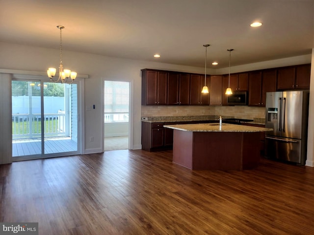 kitchen with pendant lighting, light stone counters, stainless steel appliances, and dark hardwood / wood-style floors