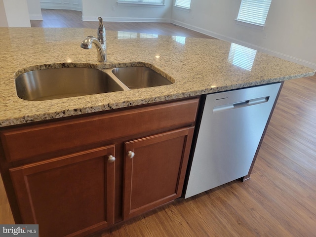 kitchen with light stone countertops, sink, stainless steel dishwasher, and light wood-type flooring