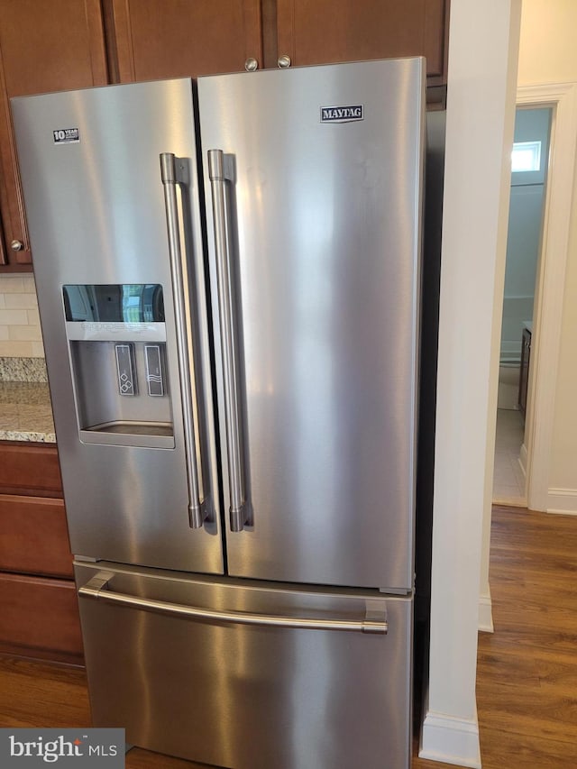 room details with light stone counters, high quality fridge, dark hardwood / wood-style floors, and decorative backsplash