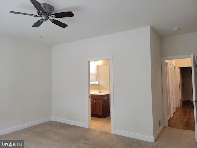 unfurnished bedroom featuring sink, light colored carpet, ceiling fan, and ensuite bathroom