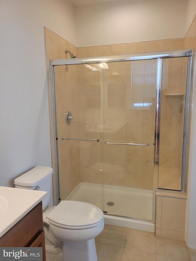 bathroom with tile patterned floors, vanity, toilet, and an enclosed shower