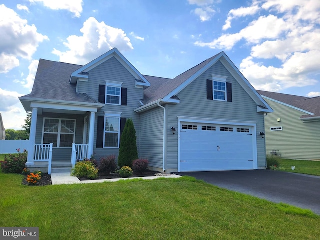 view of property featuring a garage, a front yard, and a porch