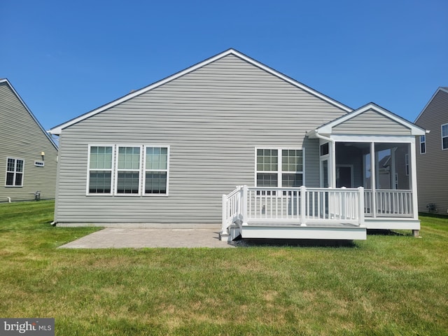 back of property with a patio, a sunroom, and a lawn