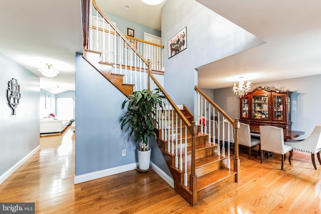 staircase with a notable chandelier and hardwood / wood-style floors