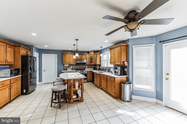 kitchen featuring ceiling fan, appliances with stainless steel finishes, tasteful backsplash, and light tile patterned floors