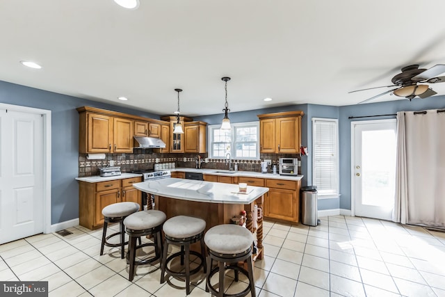 kitchen with light tile patterned flooring, ceiling fan, backsplash, and a kitchen island