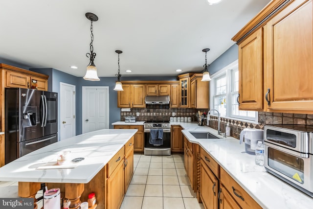 kitchen featuring tasteful backsplash, sink, hanging light fixtures, black fridge with ice dispenser, and stainless steel range with electric cooktop