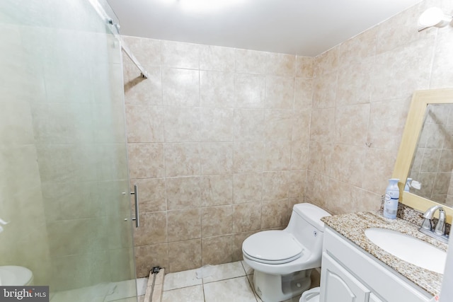 bathroom with tile patterned flooring, a shower with shower door, toilet, vanity, and tile walls