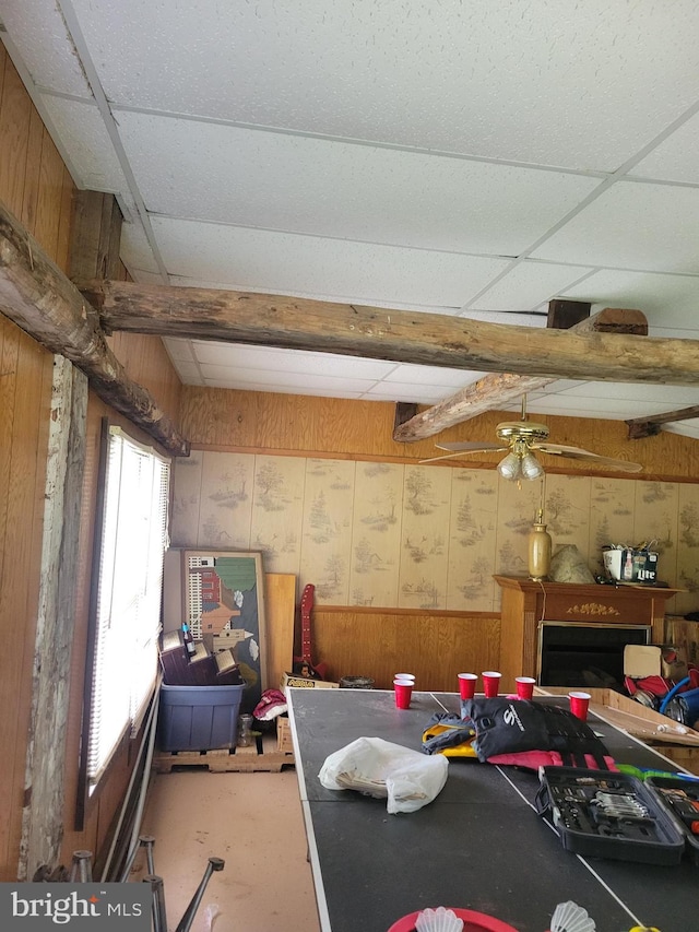 recreation room featuring ceiling fan and wooden walls