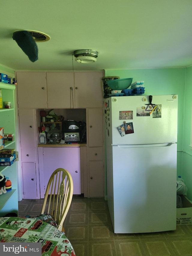 kitchen featuring white refrigerator and white cabinetry