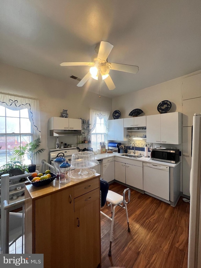 kitchen with white appliances, ceiling fan, dark wood-type flooring, sink, and white cabinets