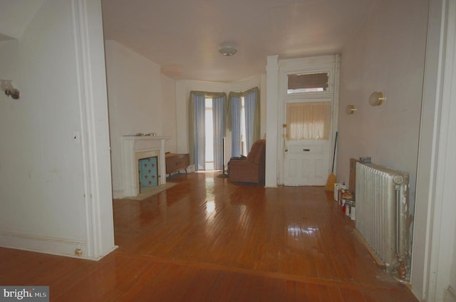 unfurnished living room featuring radiator and hardwood / wood-style flooring