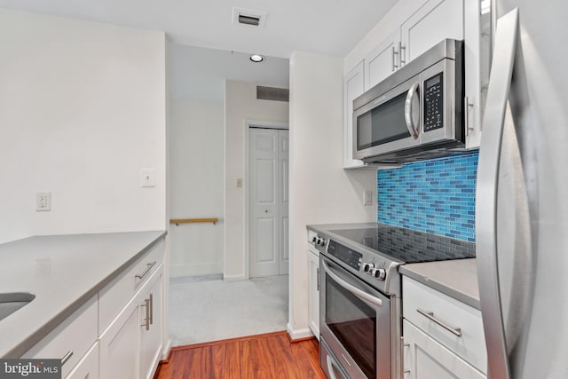 kitchen featuring decorative backsplash, white cabinetry, dark hardwood / wood-style flooring, and appliances with stainless steel finishes