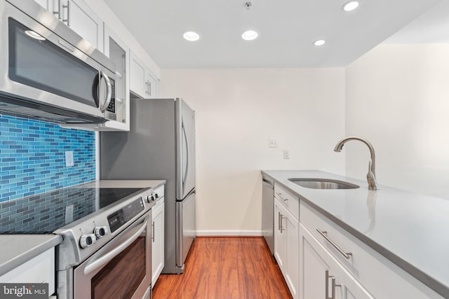 kitchen with white cabinetry, sink, stainless steel appliances, and hardwood / wood-style flooring